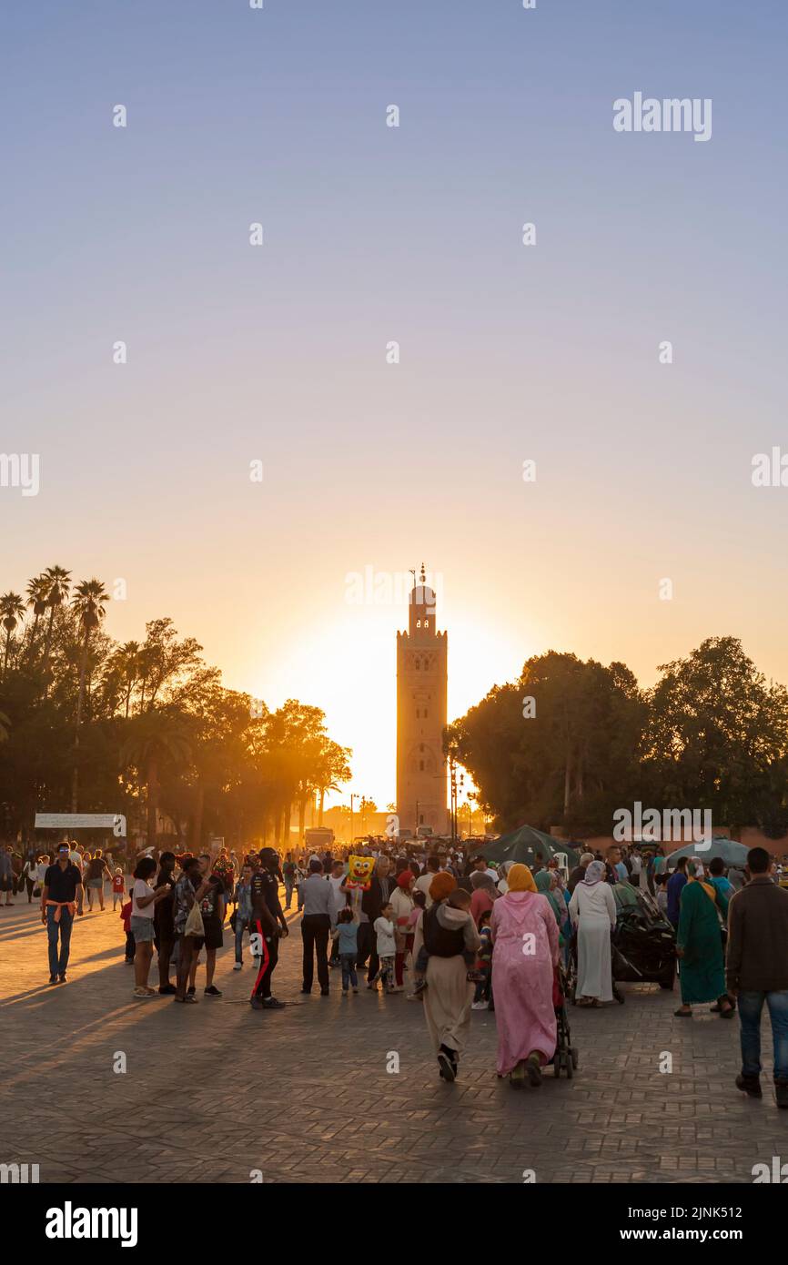 Crowd of people on Djemaa El-Fna square at sunset, minaret of Koutoubia mosque in background Stock Photo