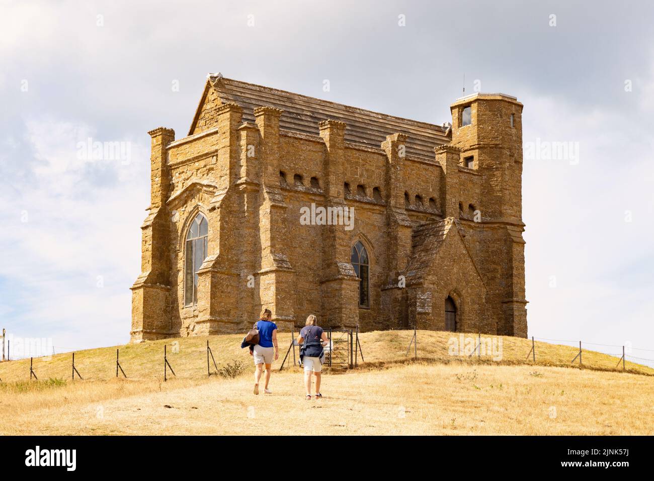 Drought UK 2022; two women walking up to St Catherines Chapel, Abbotsbury Dorset, through parched dry grass fields, August 2022 summer South England Stock Photo