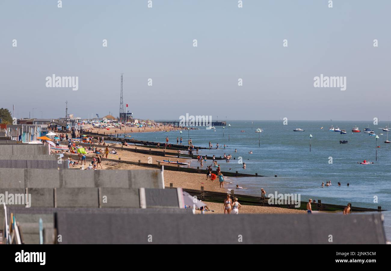 Thorpe Bay to Shoebury beach on a bright sunny summers day with people enjoying the sea and sand on a hot day and boats and yachts in the sea Stock Photo