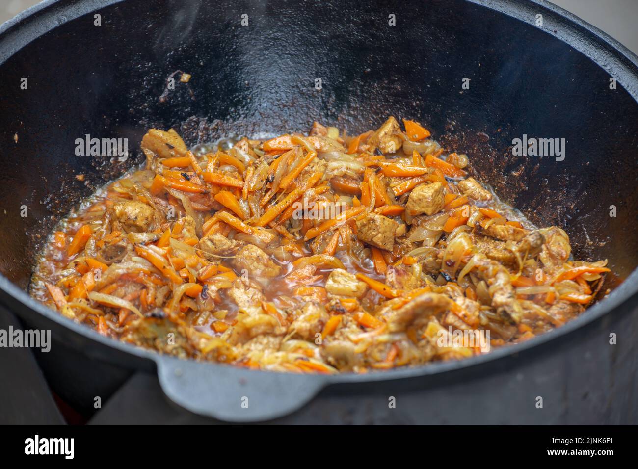 Photo of the stewed meat in cast iron in process Stock Photo
