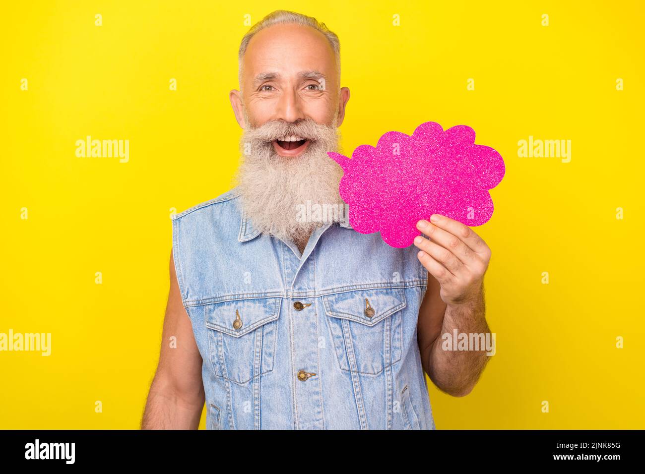 Photo of cute attractive man pensioner dressed denim vest holding speaking bubble empty space isolated yellow color background Stock Photo