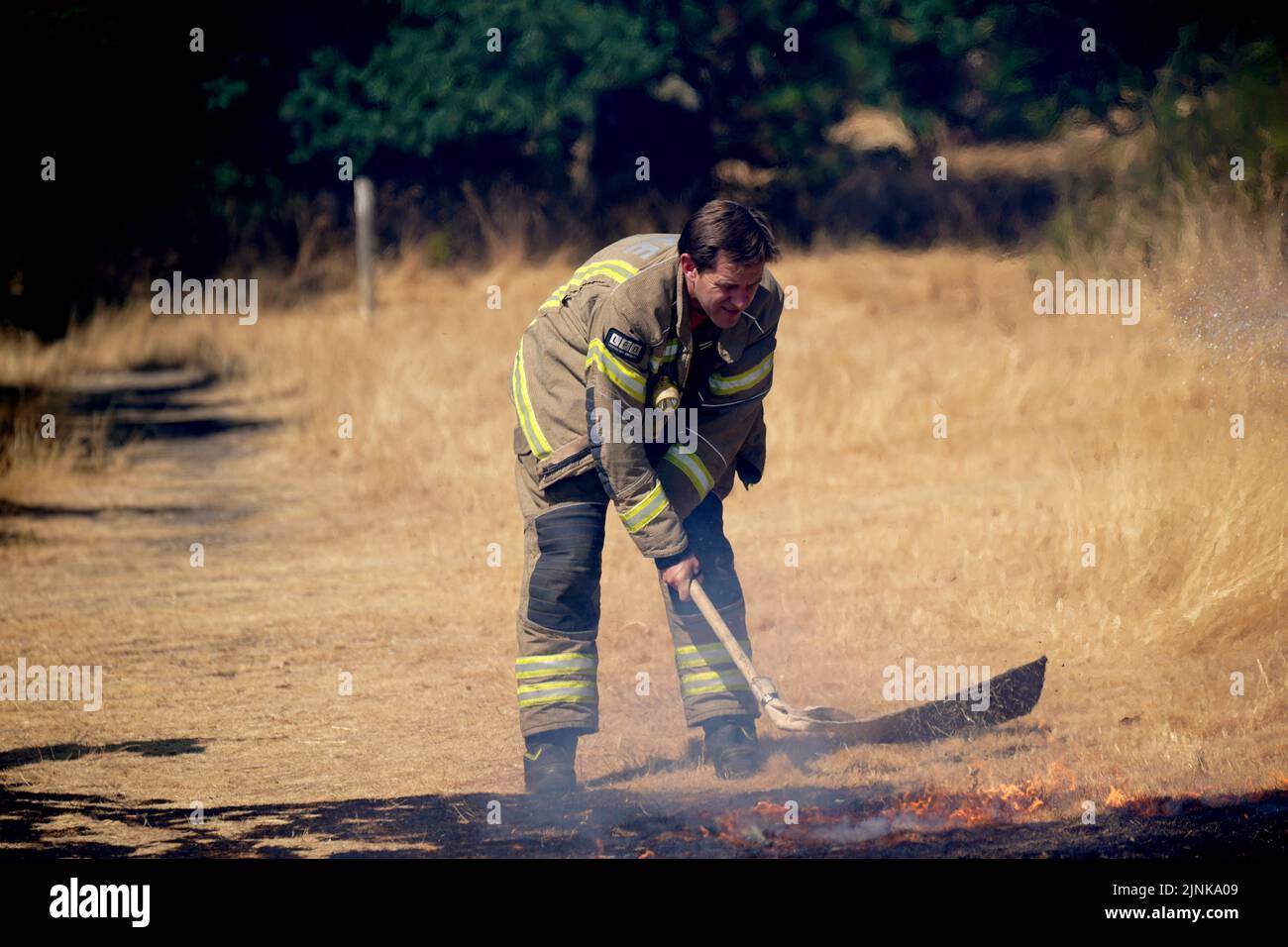A firefighter beats back flames from a grass fire on Leyton flats in east London, as a drought has been declared for parts of England following the driest summer for 50 years. Picture date: Friday August 12, 2022. Stock Photo