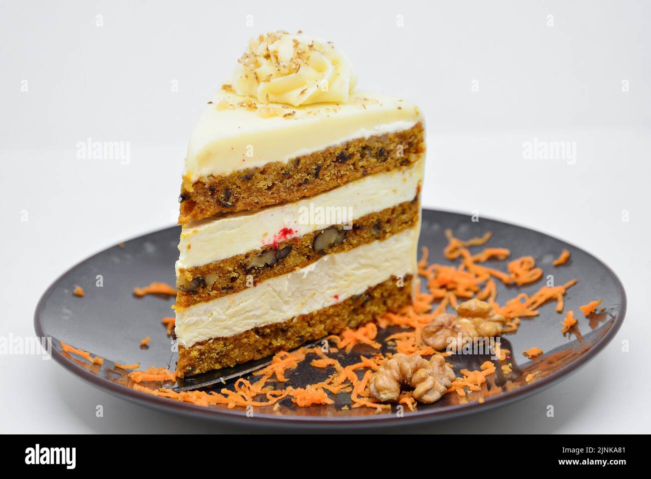 Piece of sweet carrot cake with delicious cream on white background Stock Photo