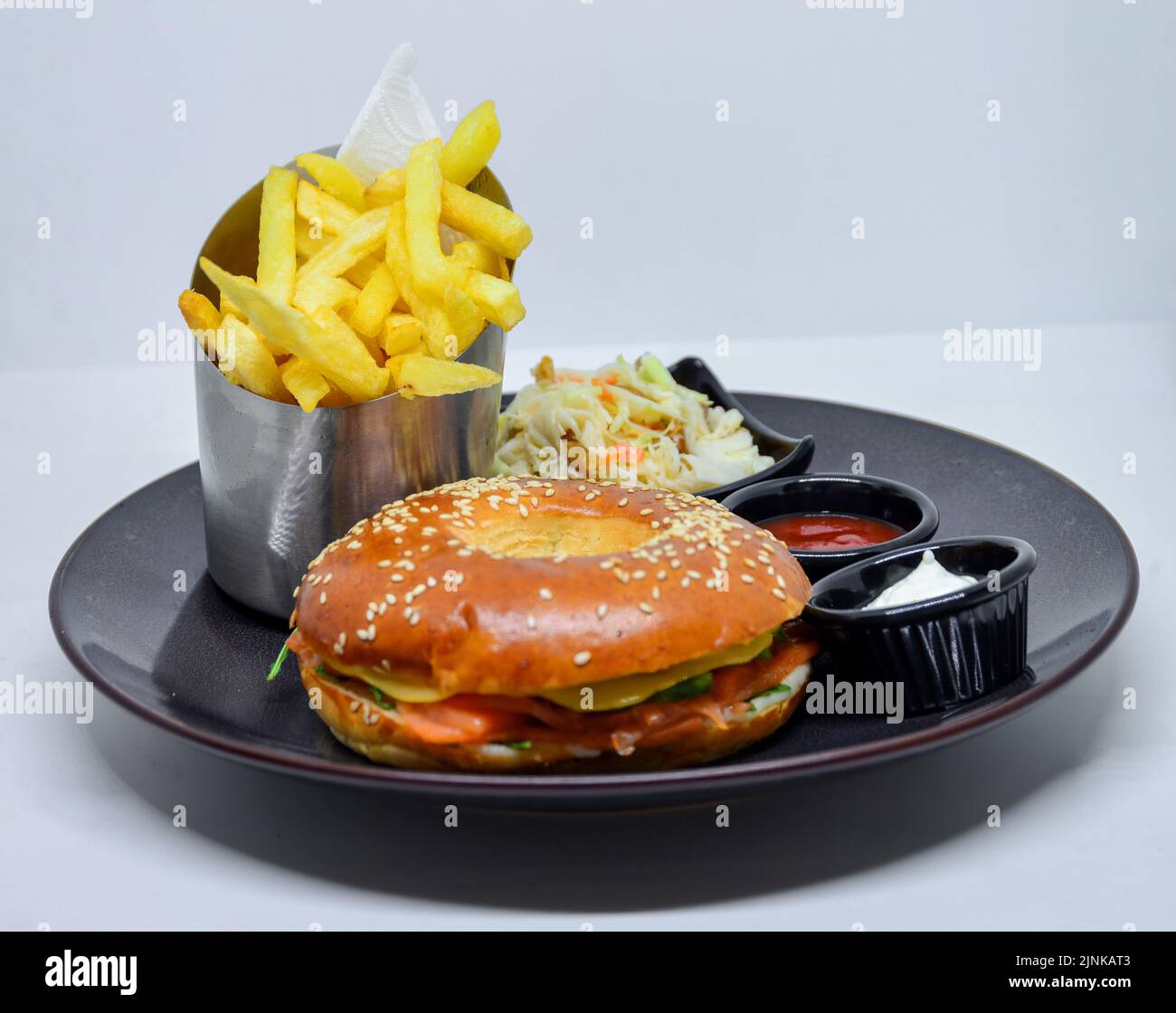 fast food menu. hamburger, french fries and salad. burger with beef stake, cheese and pickle. mayonnaise ketchup mustard on the  plate. Stock Photo