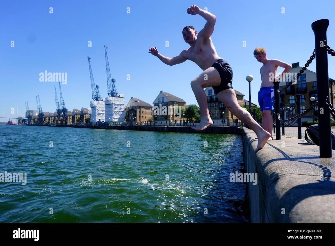 A young man jumps into Royal Victoria Dock in east London. A drought is set to be declared for some parts of England on Friday, with temperatures to hit 35C making the country hotter than parts of the Caribbean. Picture date: Friday August 12, 2022. Stock Photo