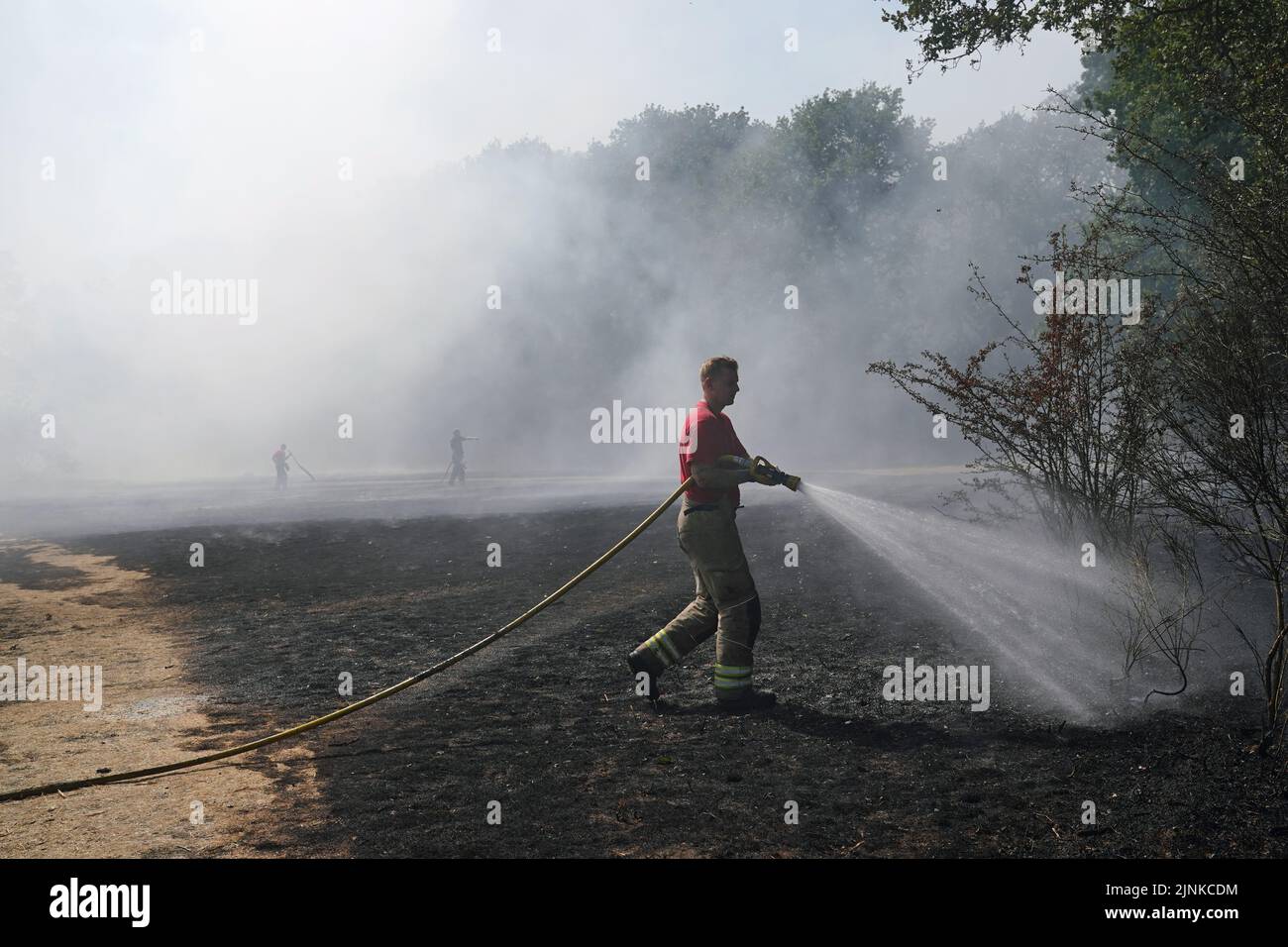A firefighter dampens down a grass fire on Leyton flats in east London, as a drought has been declared for parts of England following the driest summer for 50 years. Picture date: Friday August 12, 2022. Stock Photo