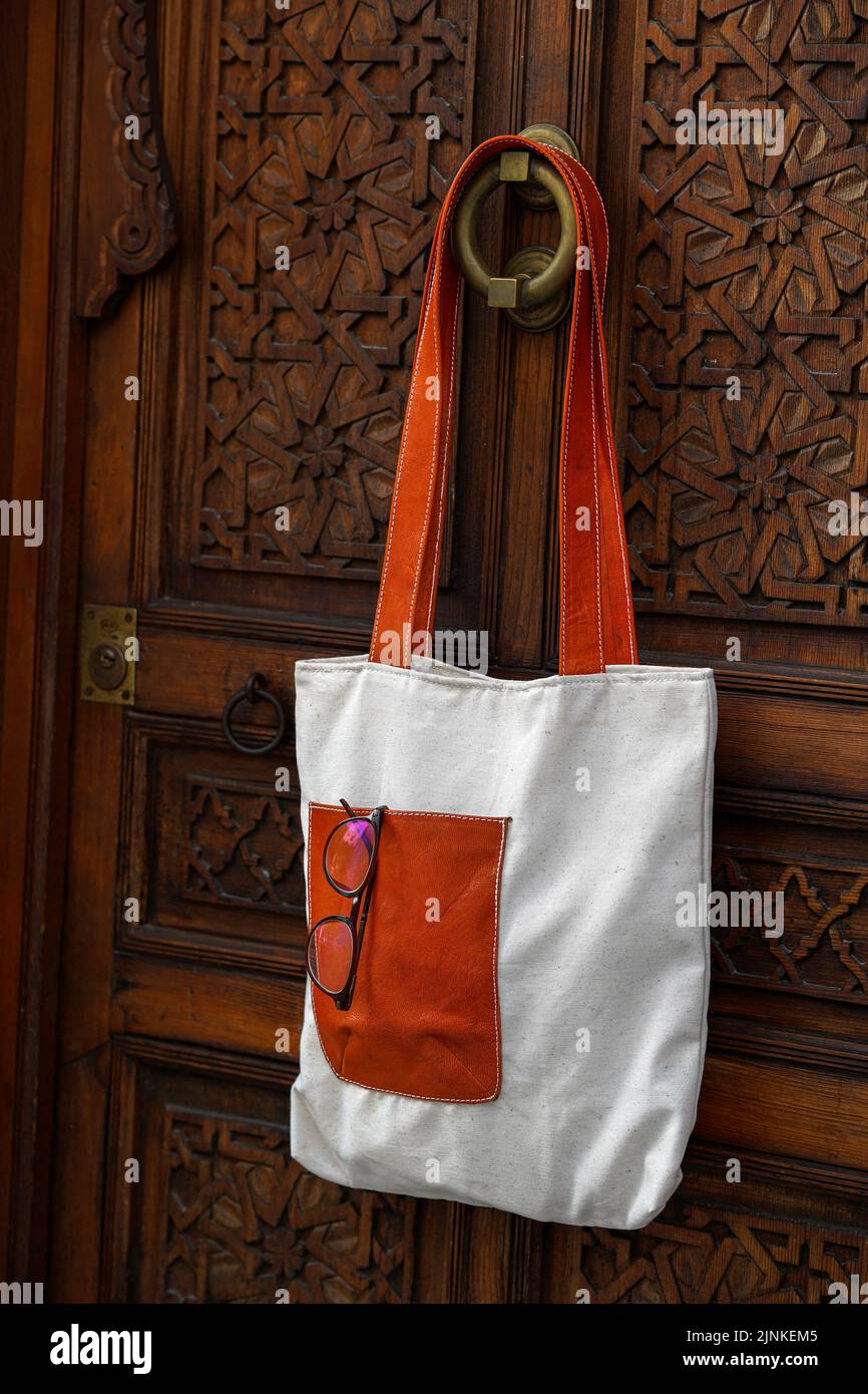 Nature eco-friendly grocery shopping bag, Jute tote bag with self handles hanging on red old wooden door moroccan Stock Photo