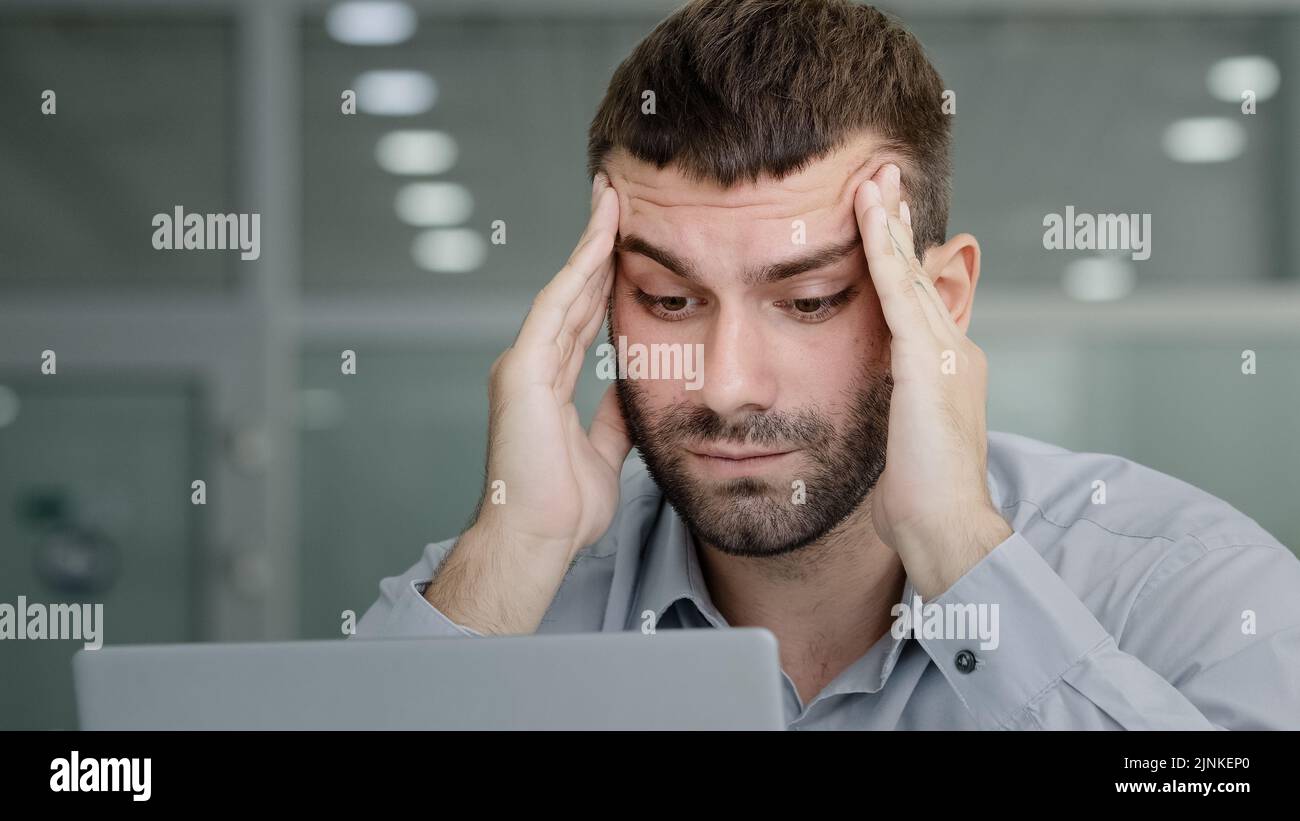 Closeup tired pensive businessman looking at laptop screen suffering