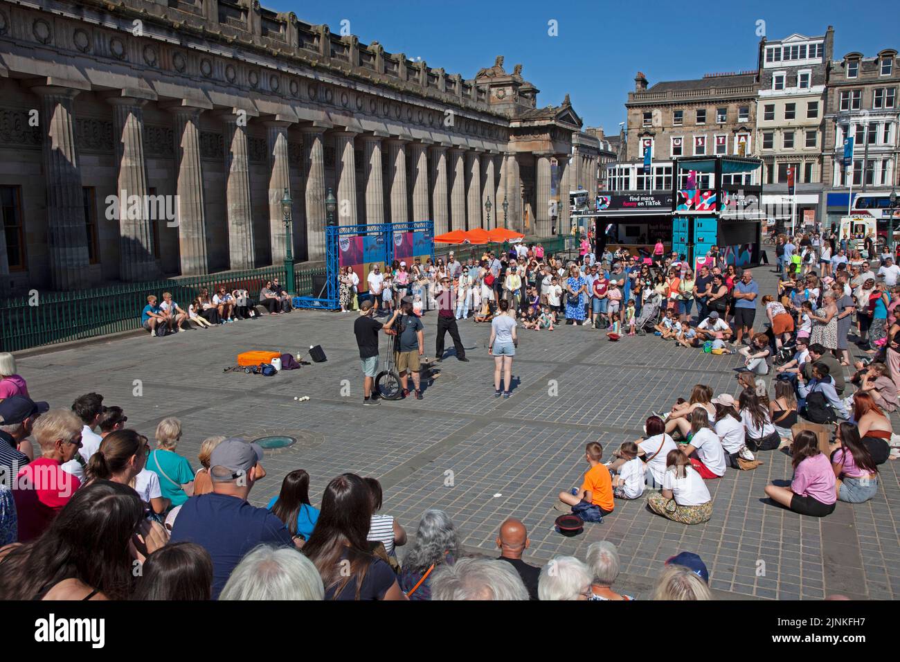 Edinburgh city centre, Scotland, UK. 12th August 2022. Edinburgh busy for the 8th day of Edinburgh Festival Fringe at various venues in the capital city for the end of the first full week. Temperature 21 degrees centigrade for those out and about. Pictured: A male street performer entertains a decent crowd at The Mound pitch, just before noon. Credit: Arch White/alamy live news. Stock Photo