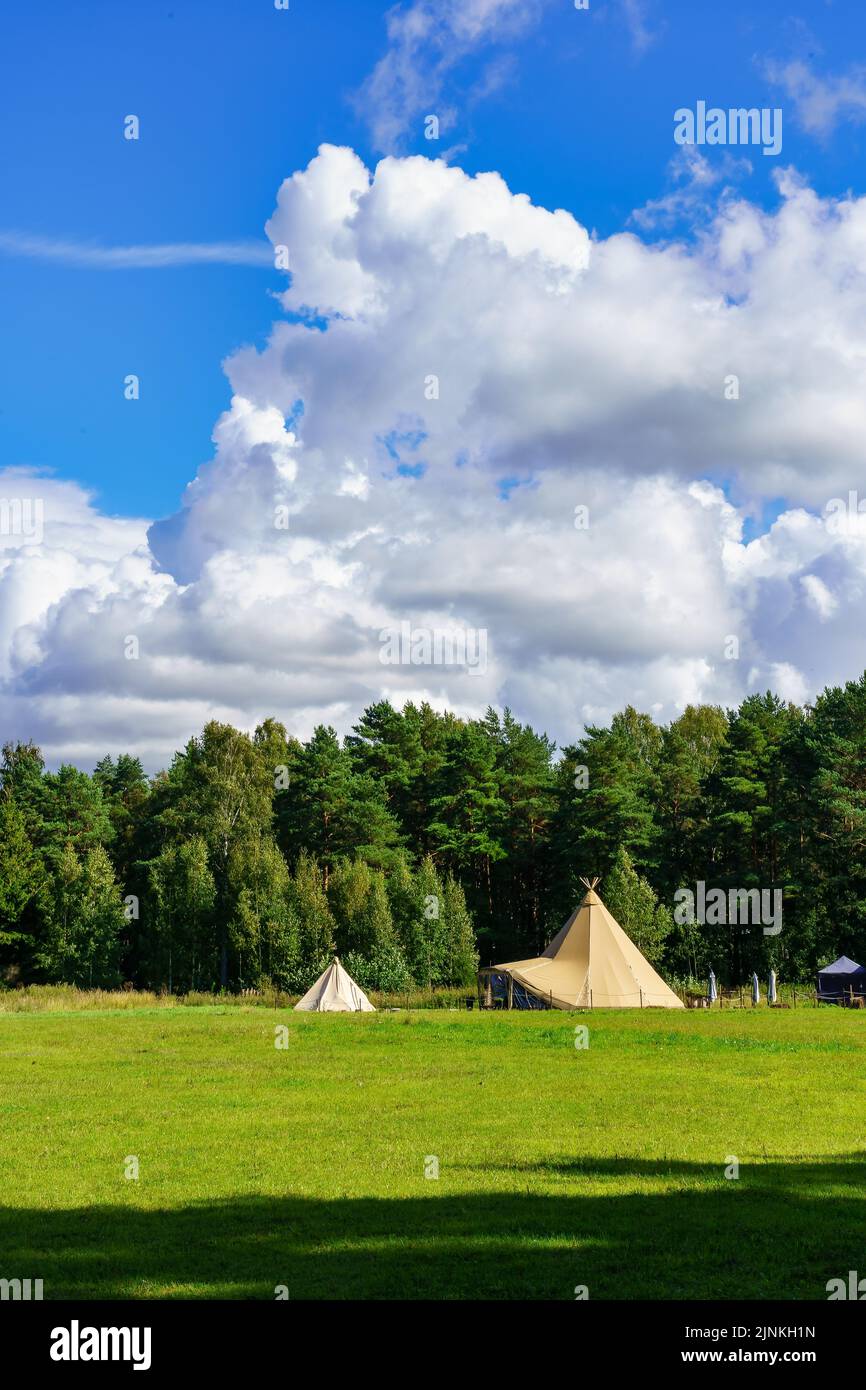 Tents in the forest on a meadow of green grass and cloudy sky Stock ...