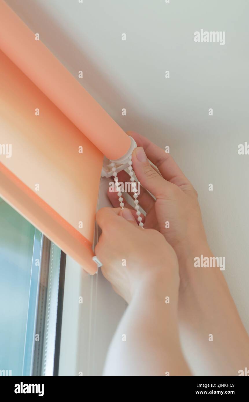 Closeup of female hands installing roller blinds on the window