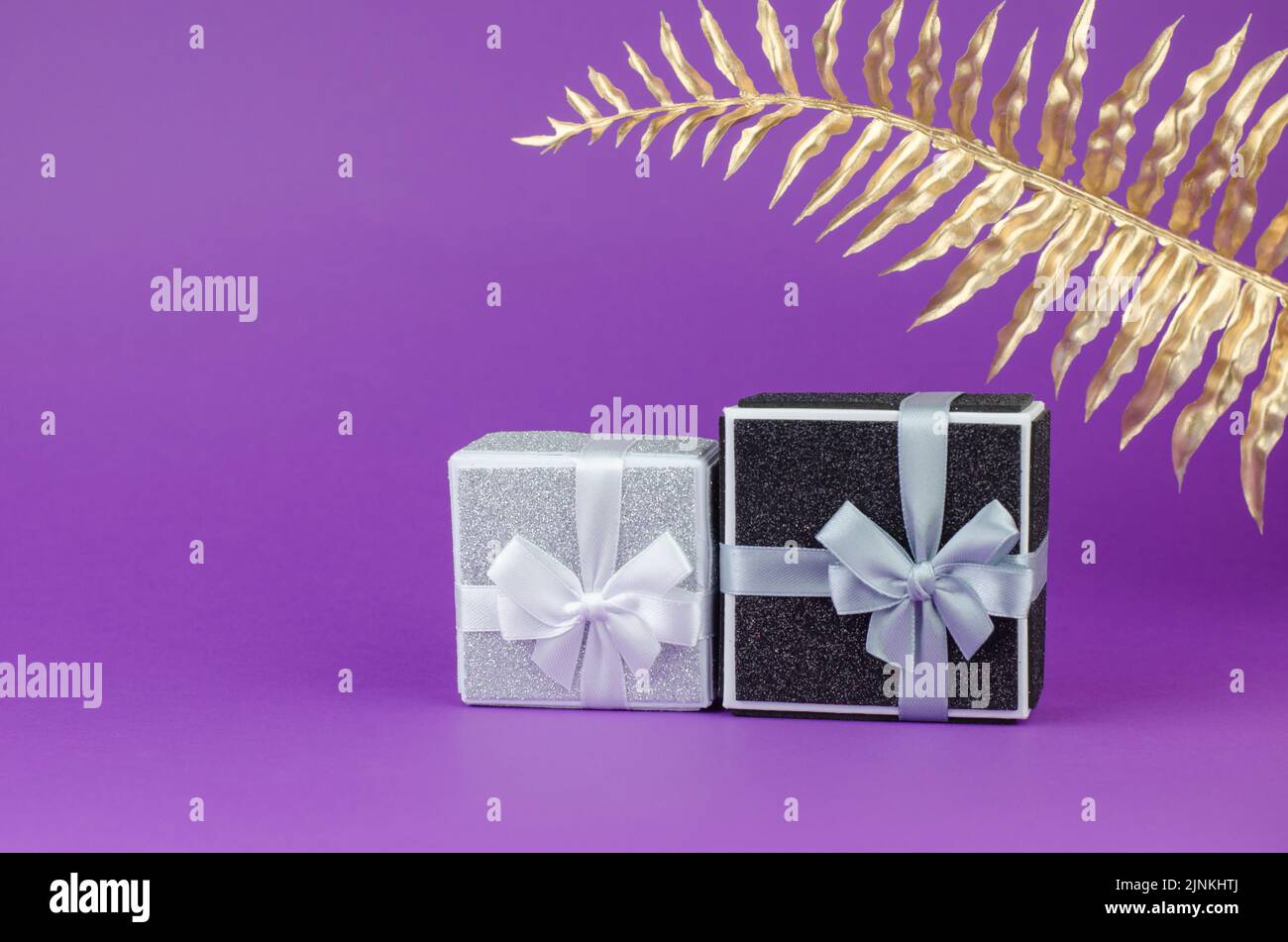 Large and small gift boxes on a purple background with a golden palm