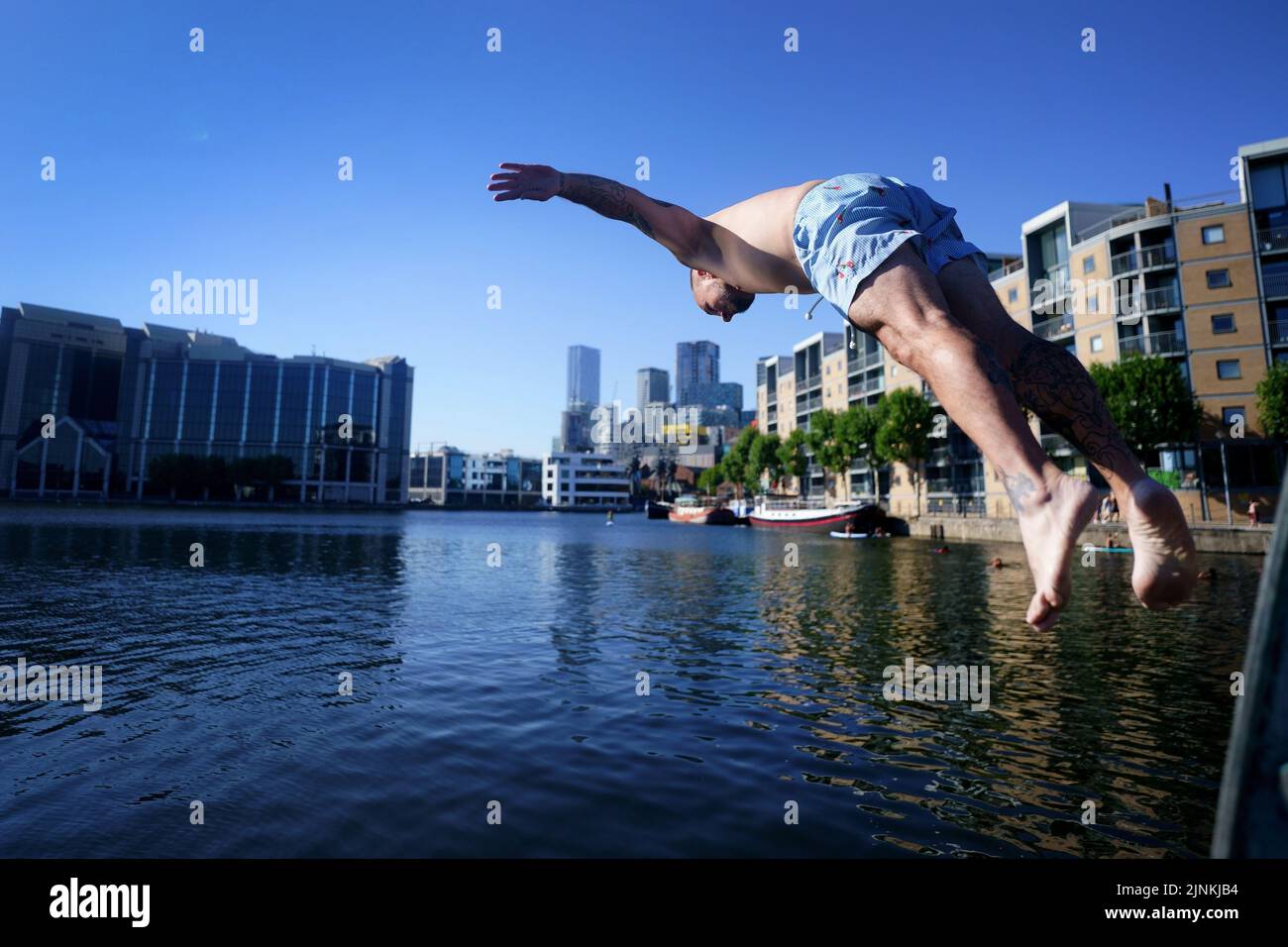 A man dives into water in the Isle of Dogs, in east London. A drought is set to be declared for some parts of England on Friday, with temperatures to hit 35C making the country hotter than parts of the Caribbean. Picture date: Friday August 12, 2022. Stock Photo