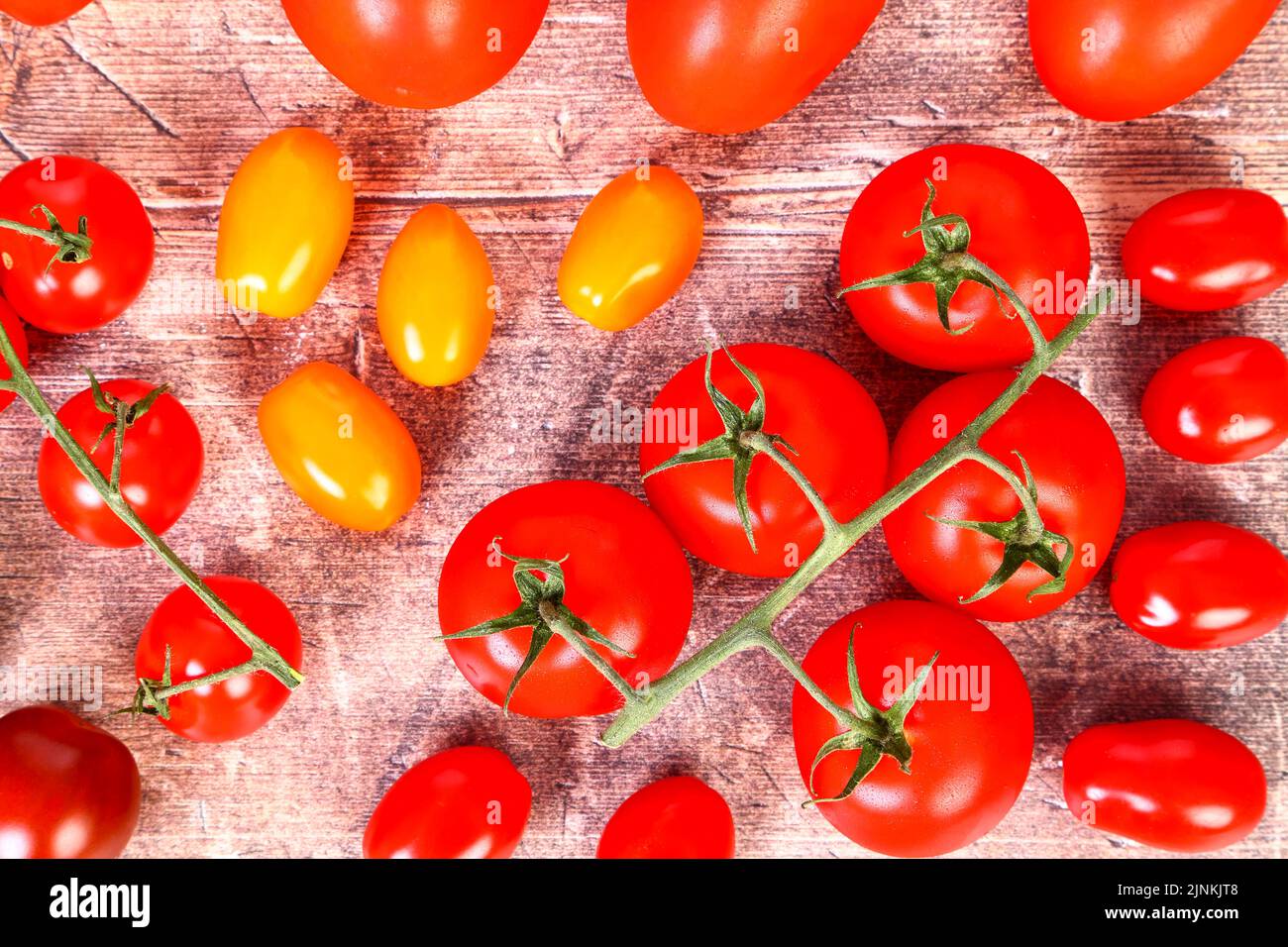 Flat lay view of a mixture of ripe tomatoes on a wooden table top Stock Photo