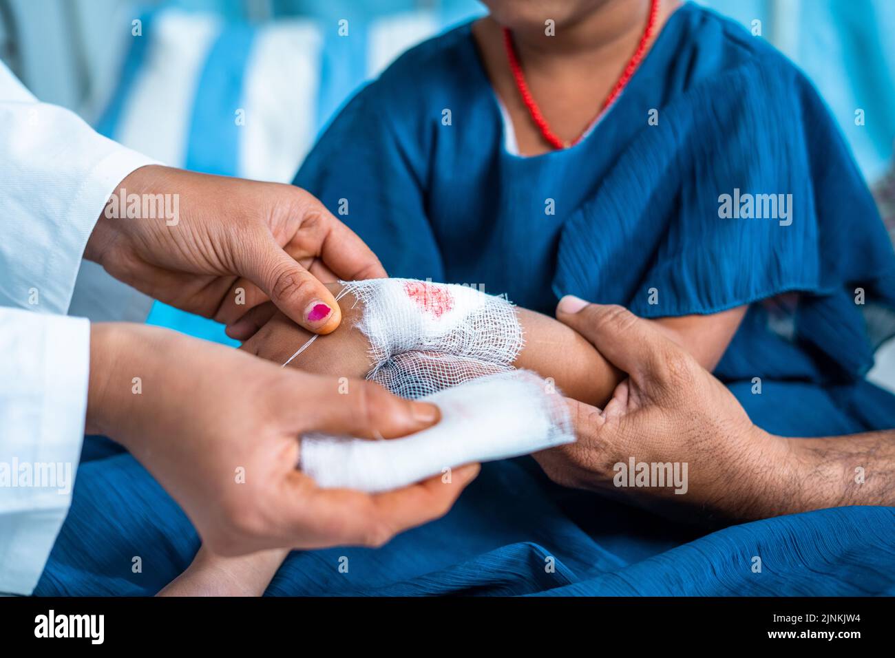 close up shot Doctor hand tying bandage to worried kids injured hand at hospital - concept of medicare, childhood mischief and medical first aid. Stock Photo