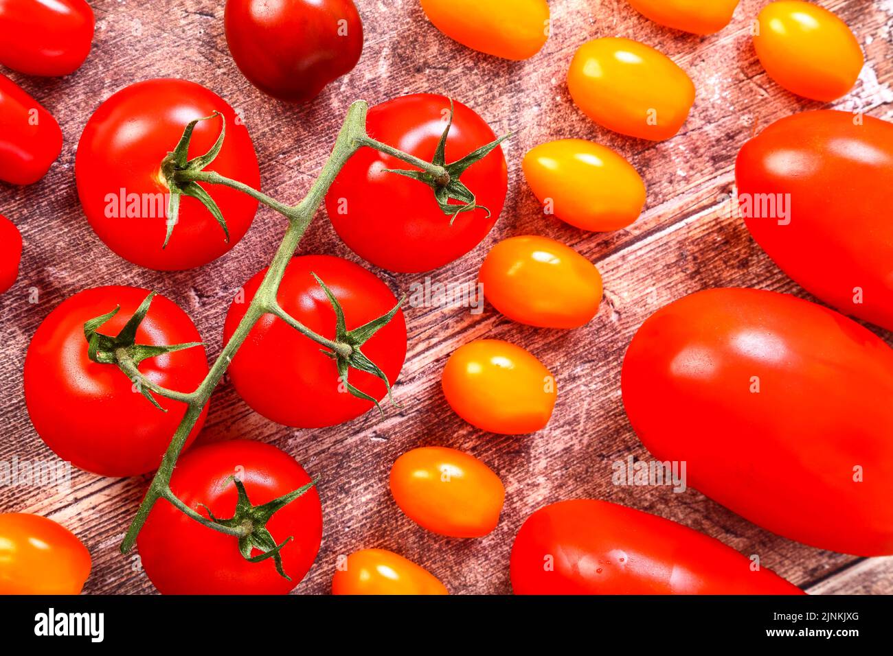 Mixed ripe tomatoes including vine, cherry and yellow in a flat lay view Stock Photo