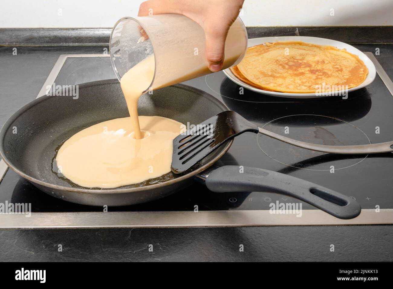 A male human hand fill dough for pancake into a frying pan while