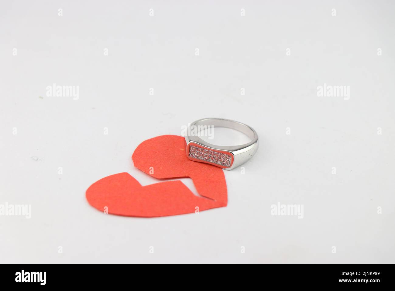 Paper broken heart and a ring showing the concept of a broken relationship in marriage or love Stock Photo