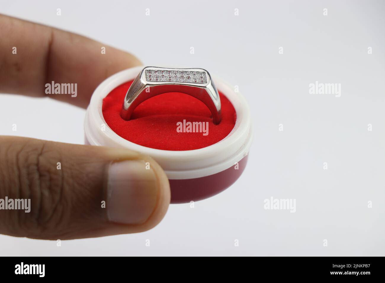 Engagement ring in a box, Silver ring in a small red jewelry box held in hand on white background Stock Photo