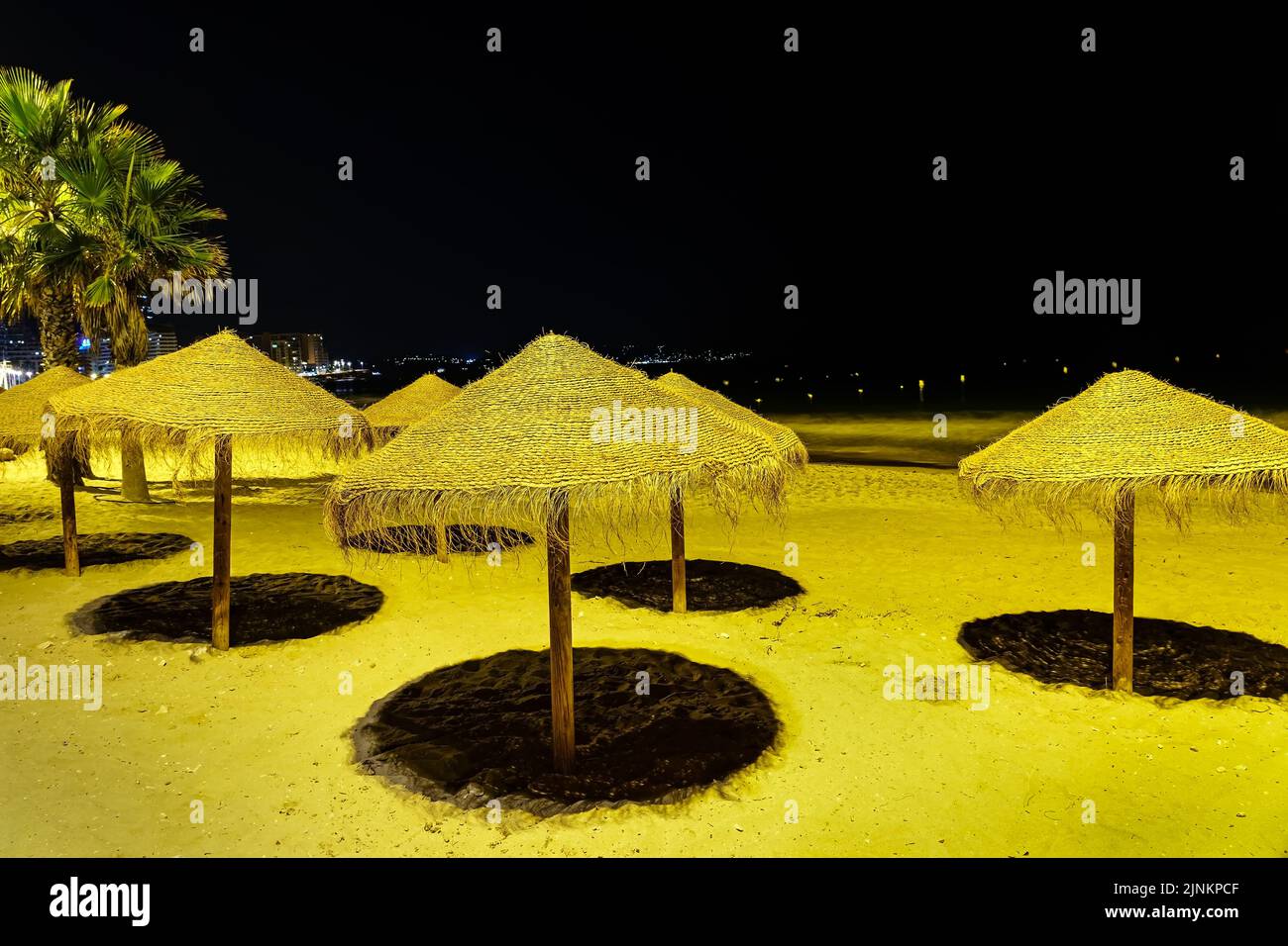 Umbrellas on the beach at night illuminated with spotlights Stock Photo