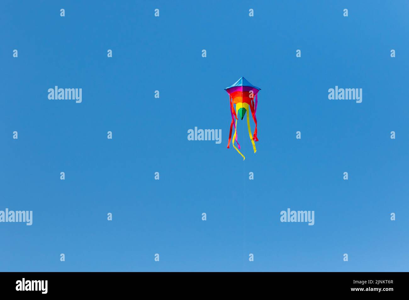 A rainbow kite flying high in the sky Stock Photo