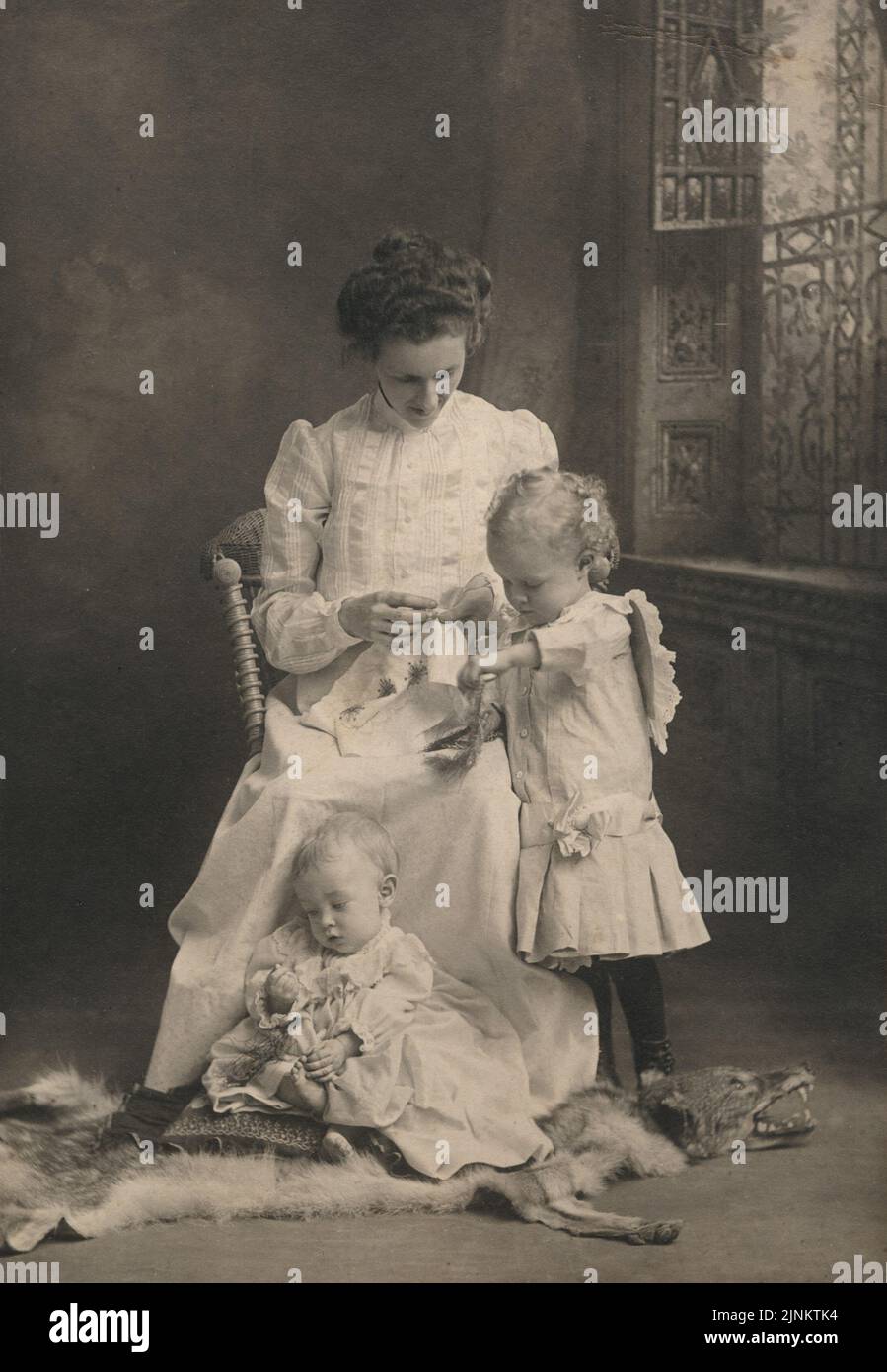 Vintage black and white photograph of mother and children in a natural candid pose for an interior studio portrait Victorian era circa 1890s Stock Photo