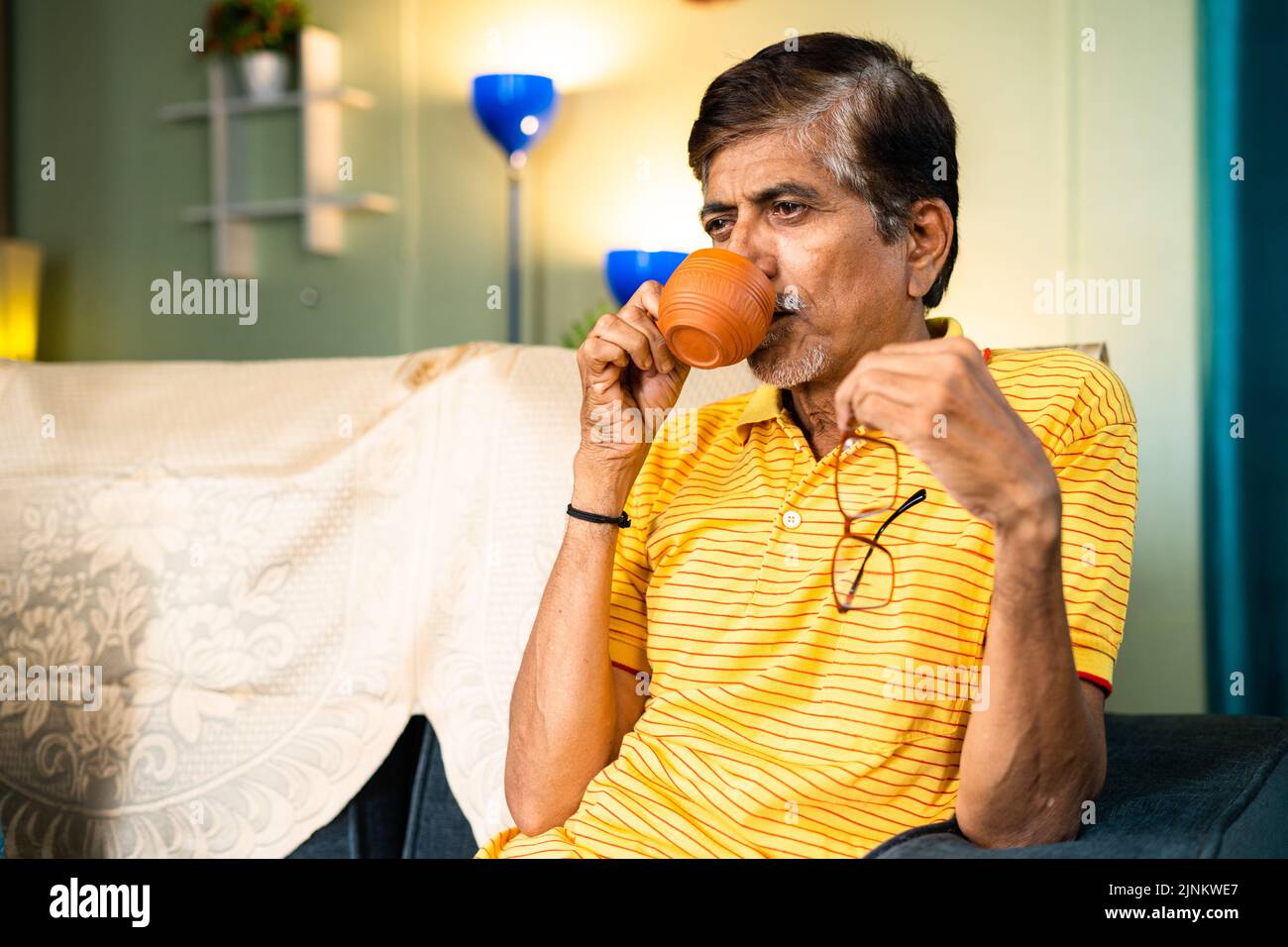 thoughtful senior Grandfather drinking tea during morning at home - concepts of refreshment, relaxation and loneliness. Stock Photo