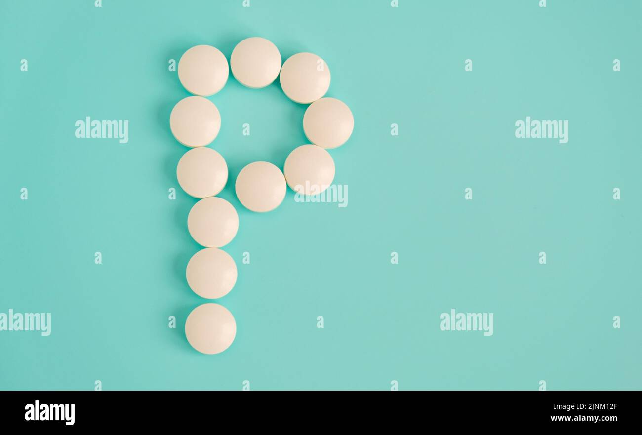 Letter P made from white pills on a blue background. White medical pills. Macro top view with copy space. Health care and pills concept, pharmaceutica Stock Photo