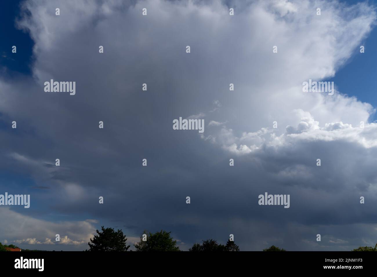 Thunderstorm clouds towering in a bright blue summer sky Stock Photo