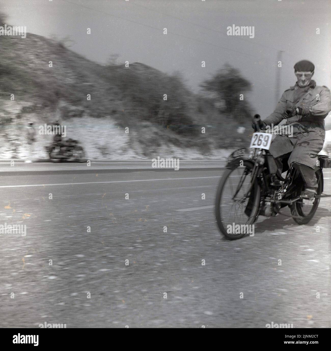 1960, historical, a male competitor in coat and hat, no 269, travelling on his old motorised bicycle on the Brighton Road (A23) taking part in the London to Brihton veteran car run, East Sussex, England, UK. The run is open to vehicles built before 1905. Stock Photo