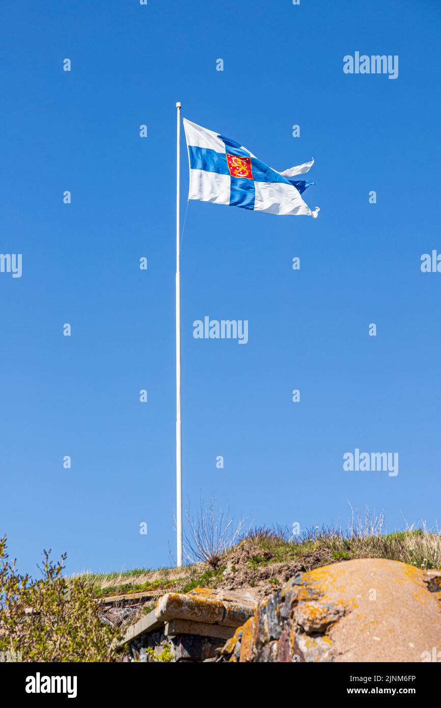 The Finnish flag set against a blue sky flying over the Suomenlinna Fortress at Kustaanmiekka on the island of Suomenlinna off Helsinki, Finland Stock Photo