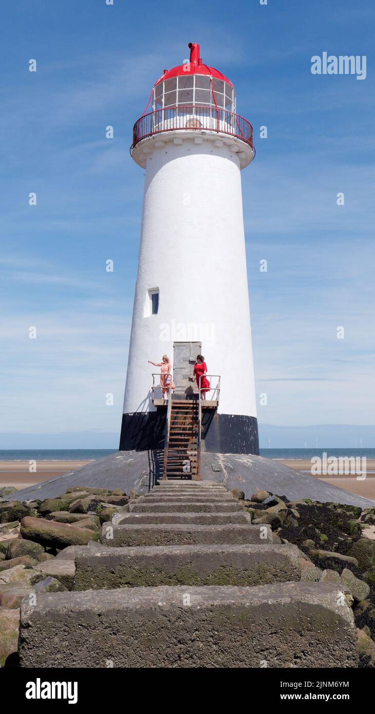 Talacre, Flintshire, Wales, Aug 07 2022: Point of Ayr Lighthouse aka Talacre Lighthouse, a Grade II listed building situated on the beach. Two women i Stock Photo