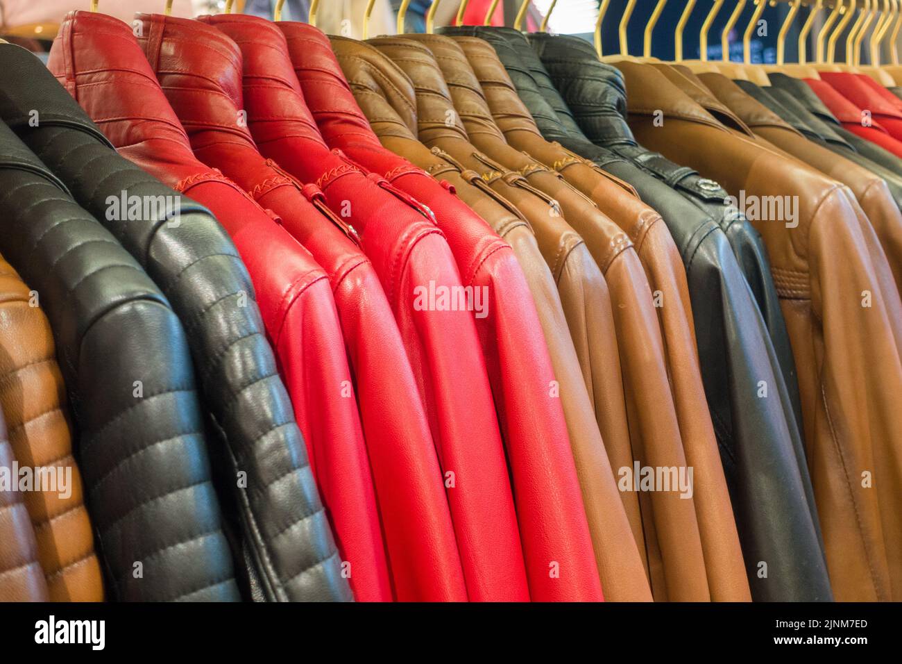 Leather jackets on rack in store. Beautiful collection of different color leather jackets. Stock Photo