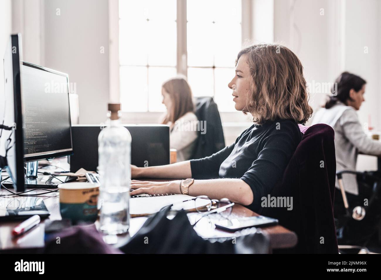 Yound devoted female software developers team working on desktop computer in IT statup company. Stock Photo