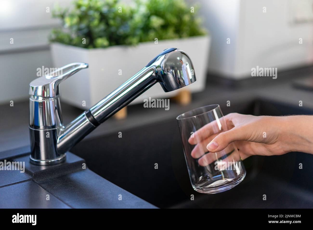 Filling a glass with drinking water from the kitchen tap Stock Photo