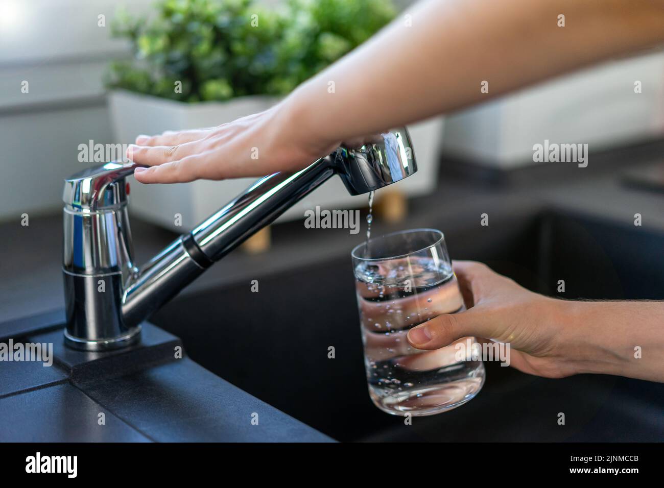 The woman's hand turns off the faucet in the kitchen. Stock Photo