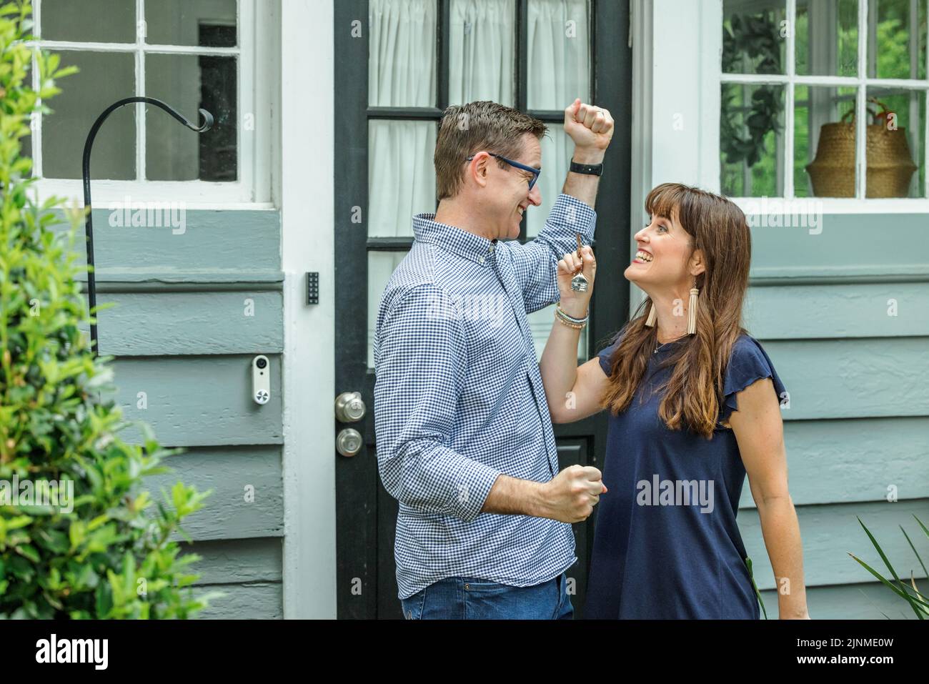 A woman holding up the house key to her husband for their new home in ...