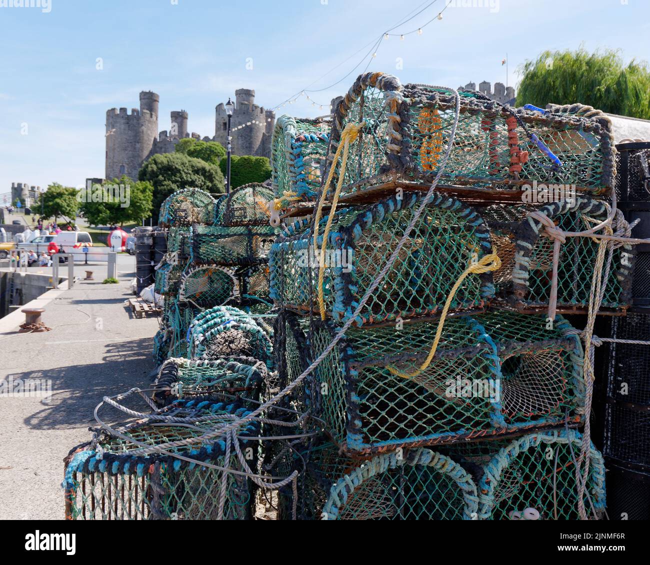 Conwy, Clwyd, Wales, August 07 2022: Fishing baskets stacked in the harbour with Conwy Castle in the background. Stock Photo