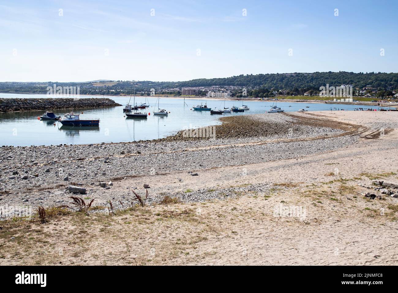 Boats at anchor at low tide in Rhos on Sea harbour with its sandy beach on a summer's day in North Wales Stock Photo