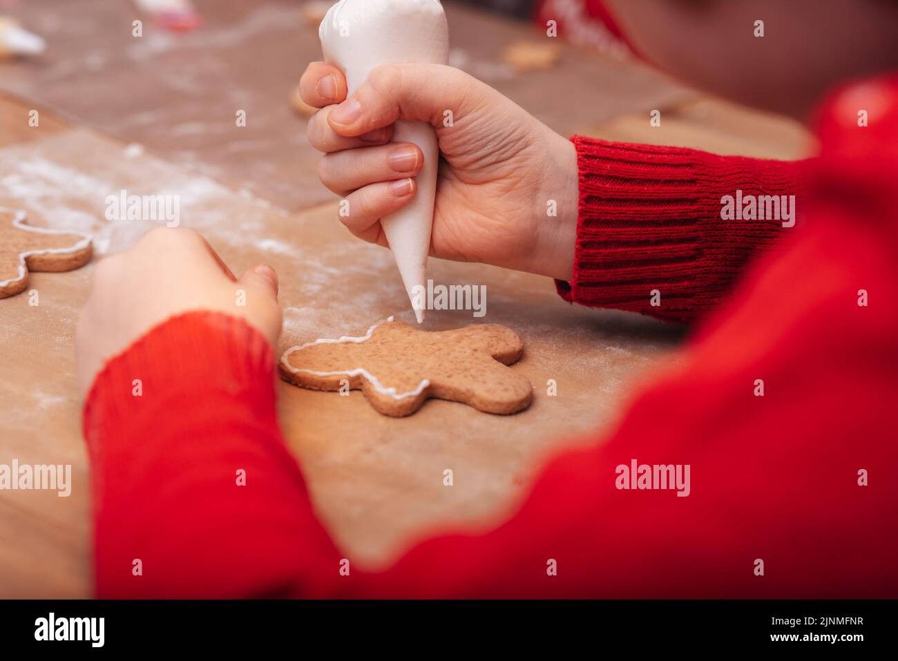 Baking holiday cookies. Child decorates Christmas cookies with icing