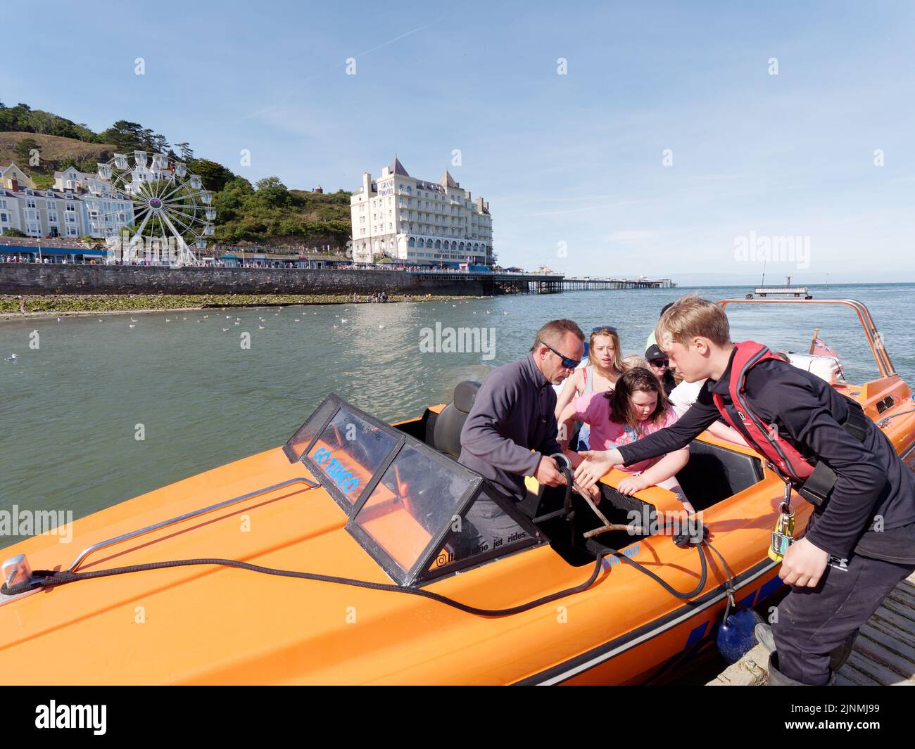 Llandudno, Clwyd, Wales, August 07 2022: Tourists getting out of a boat with the big wheel and Grand Hotel in the background. Stock Photo