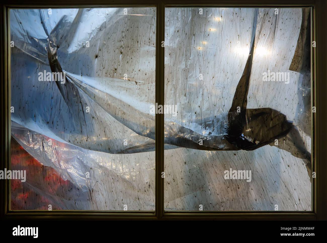 Window frame covered with dirty stained plastic film inside Stock Photo