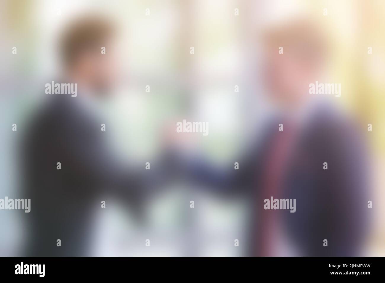 blurry background with two businessmen shaking hands Stock Photo