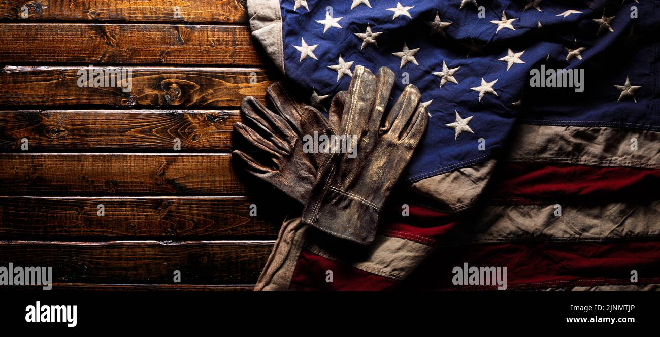 Old and worn work gloves on large American flag - Labor day background Stock Photo