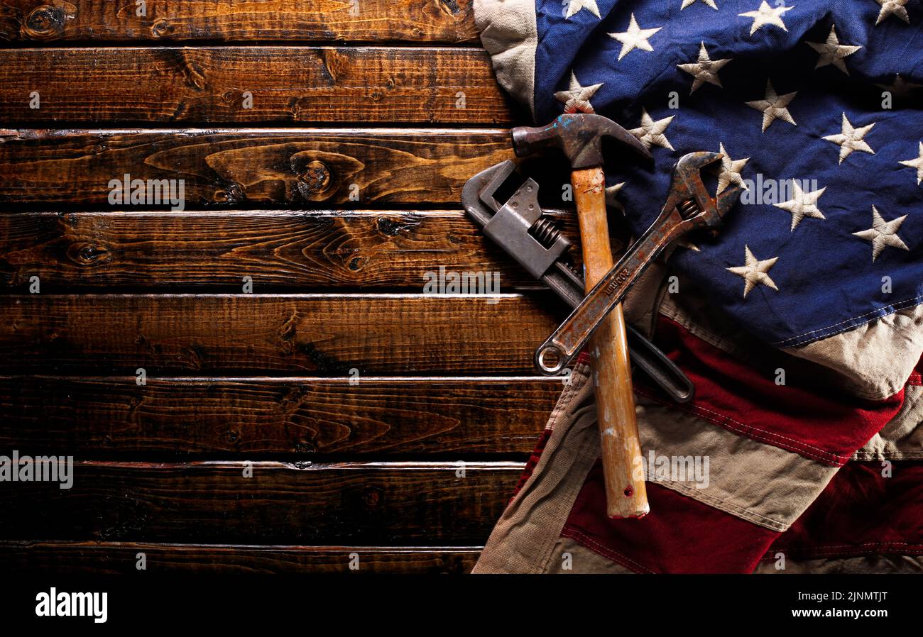 Old and worn work tools on large American flag - Labor day background Stock Photo