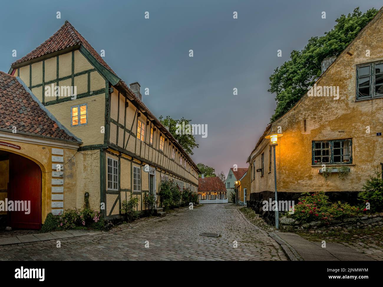 The old half-timbered museum and ancient houses on a cobbled street in dim evening light in Mariager, Denmark, August 7, 2022 Stock Photo