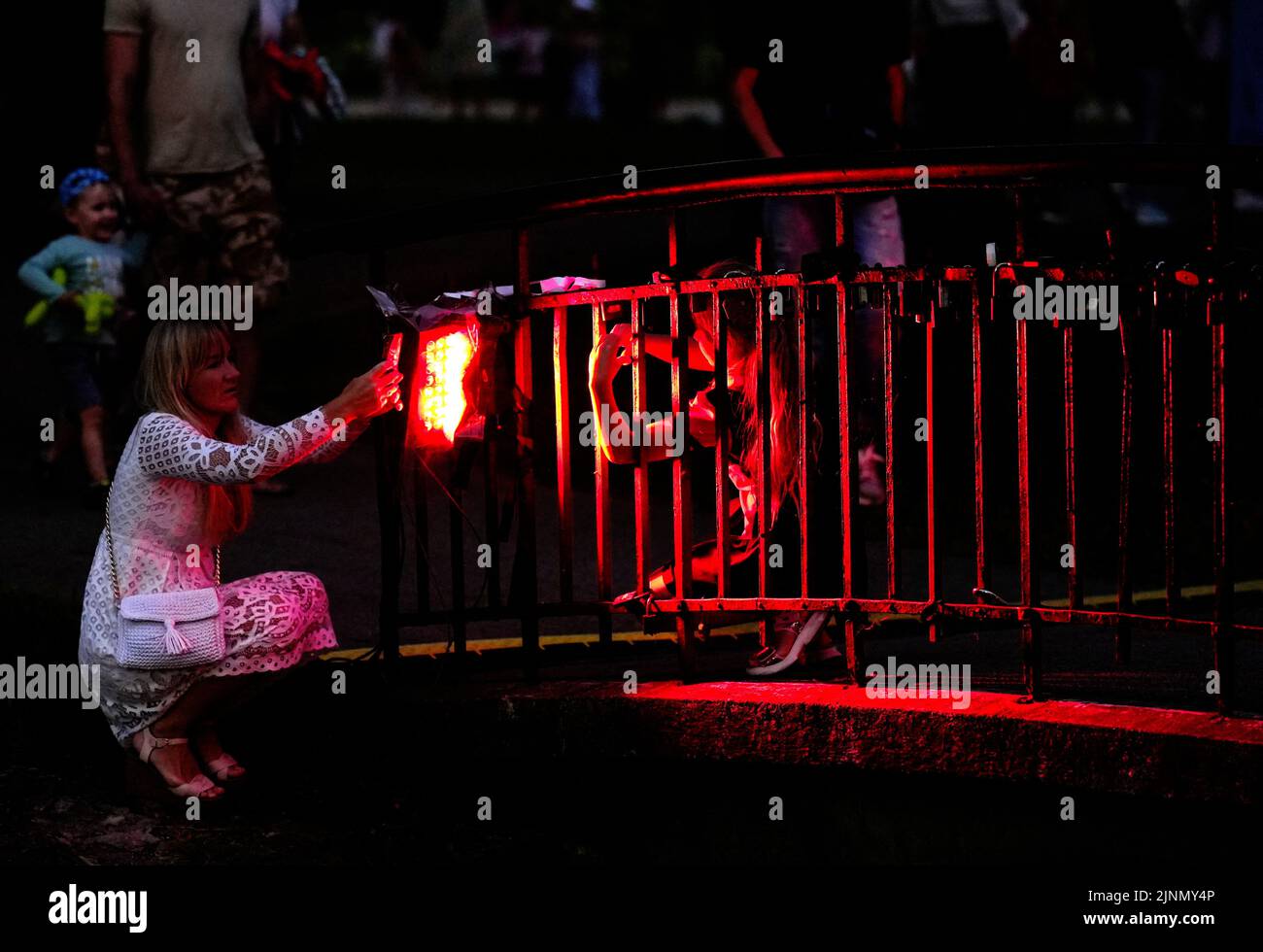 A woman takes a picture on a colourfully lit bridge during the 'Night in the park' event in Riga, Latvia August 12, 2022. REUTERS/Ints Kalnins Stock Photo