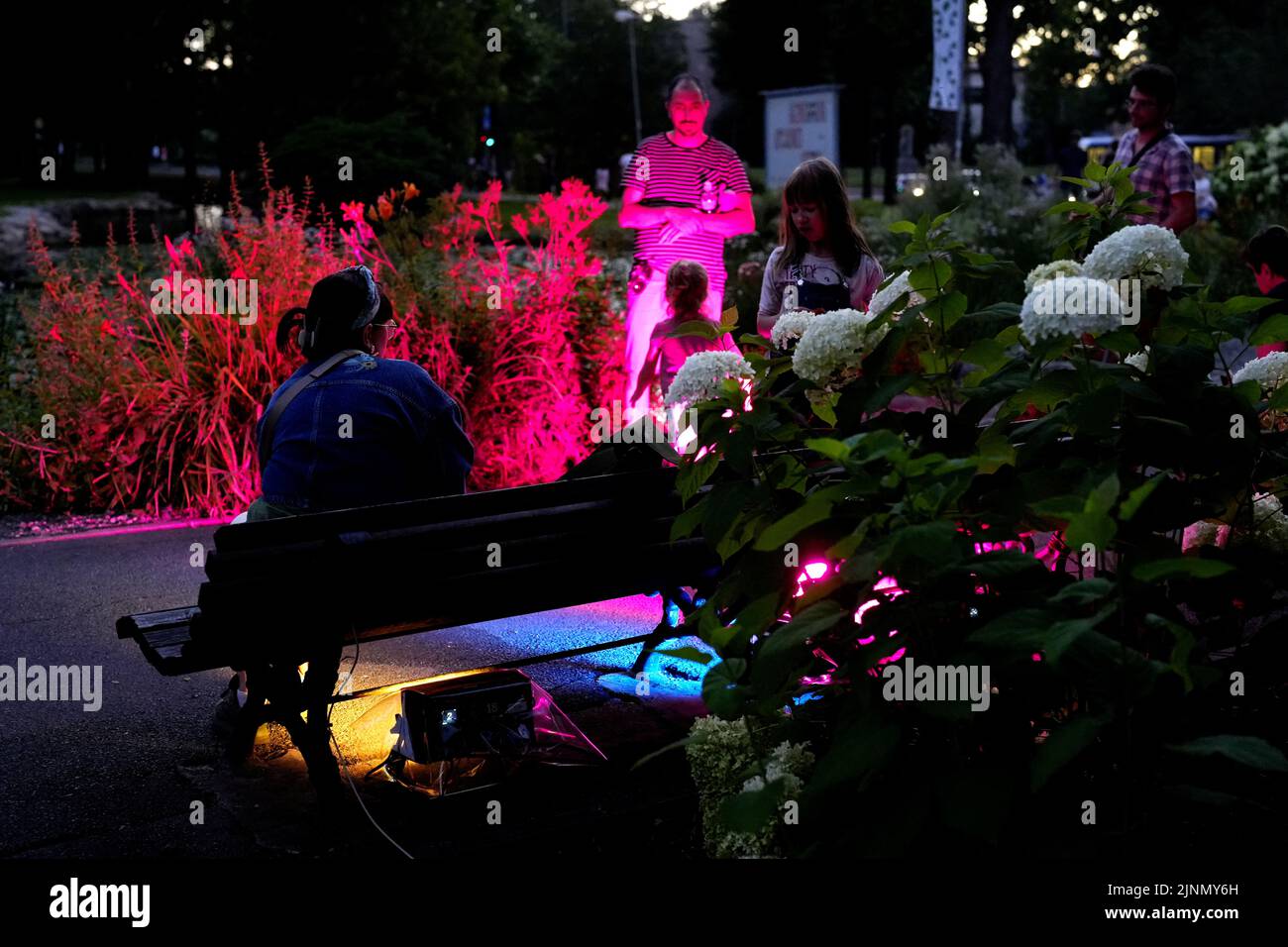 People sit on a colourfully lit bench during the 'Night in the park' event in Riga, Latvia August 12, 2022. REUTERS/Ints Kalnins Stock Photo
