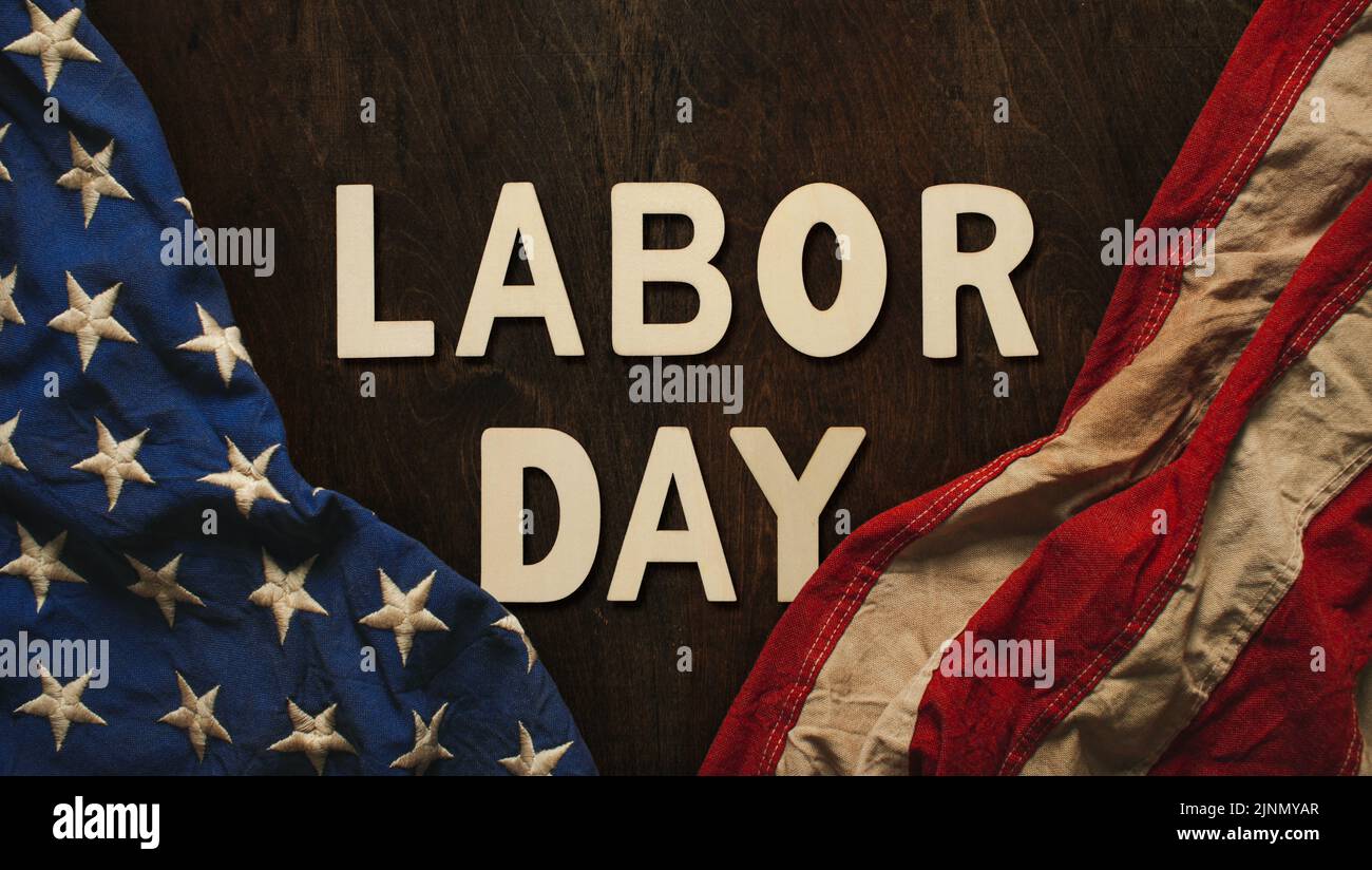 Vintage US American flag crumpled on worn wooden background with Labor Day text, celebrating American workers. Stock Photo