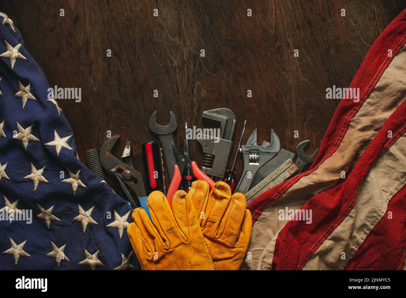Worn work gloves on tools with US American flag. Made in USA, American workforce, blue collar worker, or Labor Day concept. Stock Photo